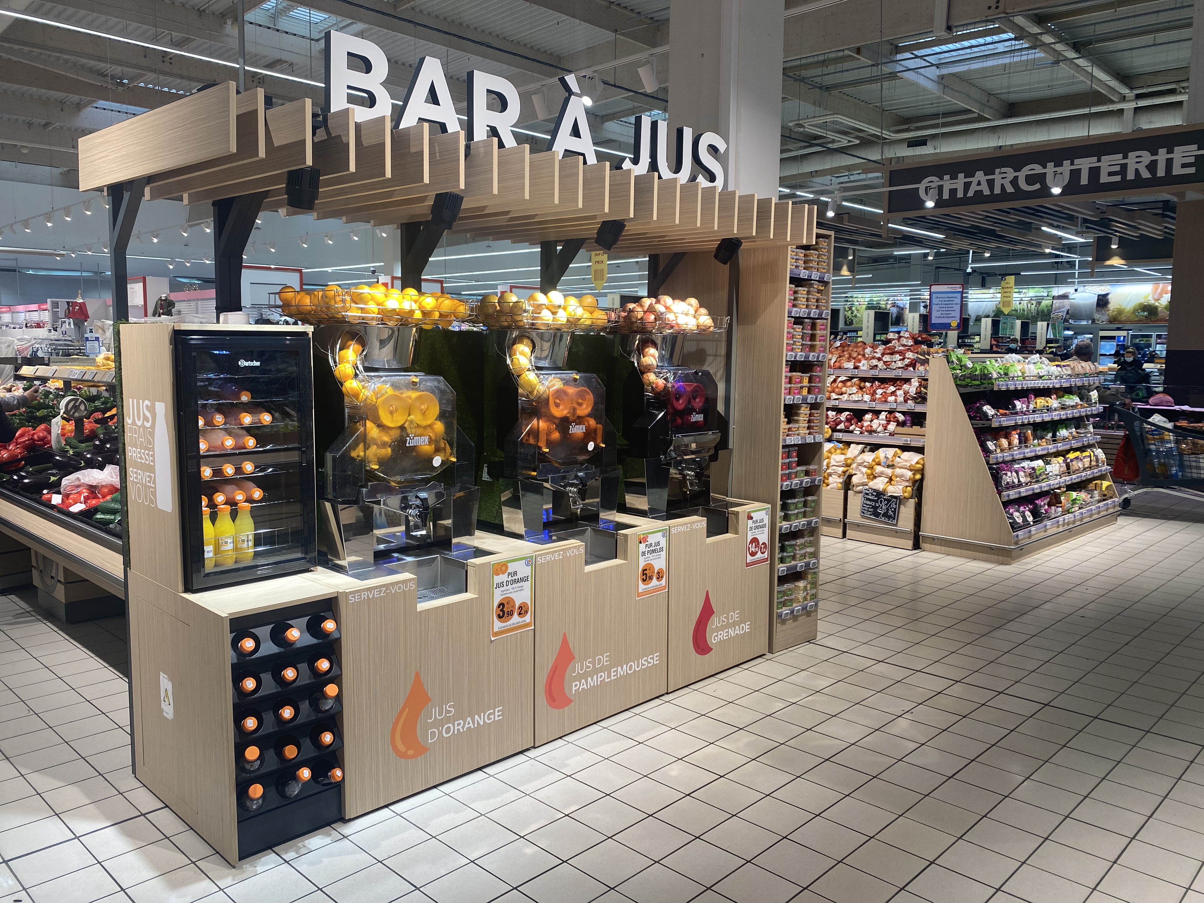 Vue large du bar à jus Zumex dans un rayon fruits et légumes